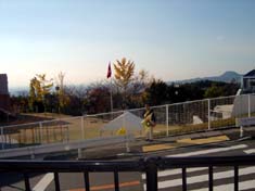 もう、みんな来るかな！（坂井田さん横断歩道の前で準備ＯＫ！）学園旗、銀杏の葉そして右手向こうには「甲山」。.JPG